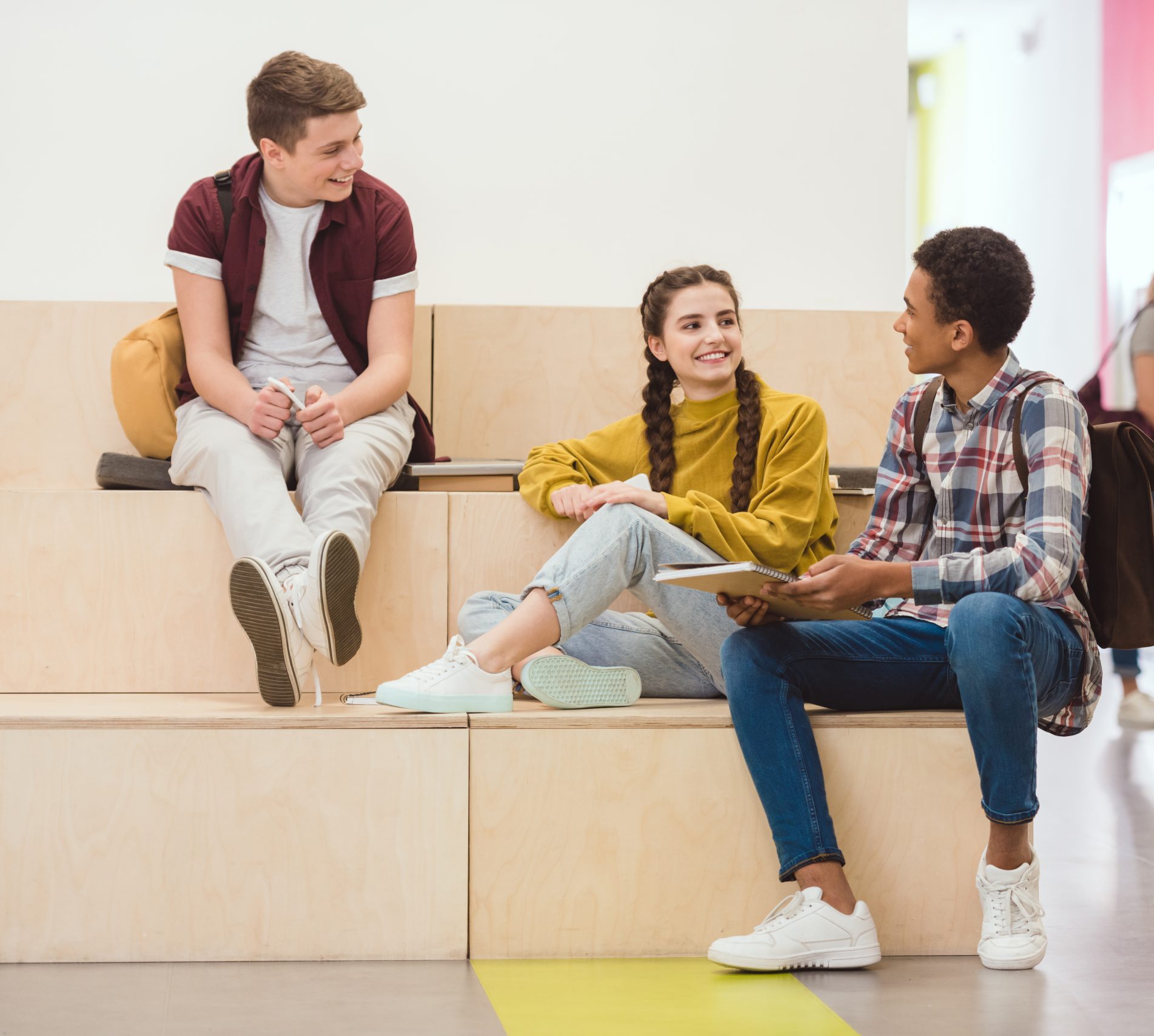 high school students sitting in lounge zone at school corridor