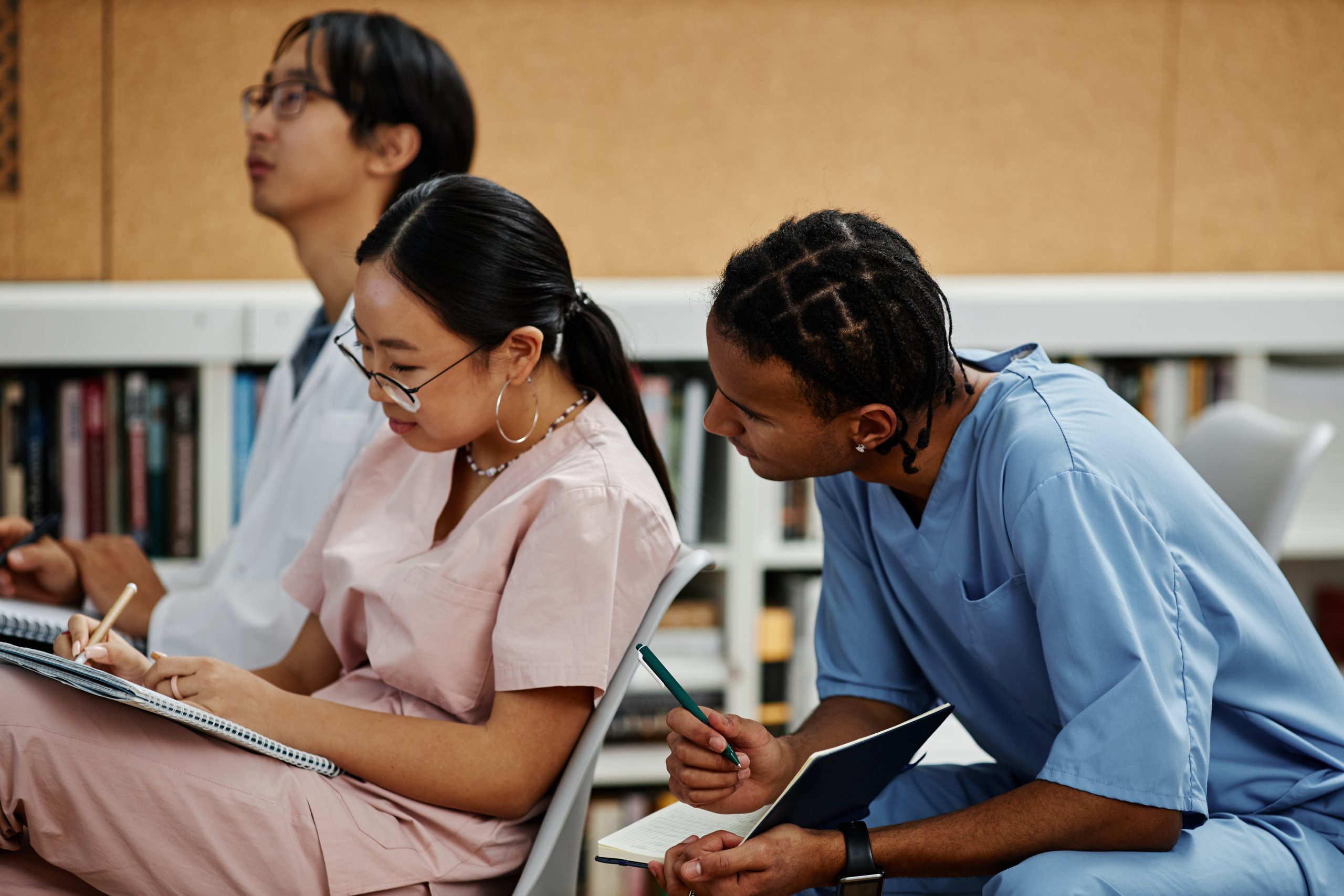 Two young med students talking in audience during lecture or seminar
